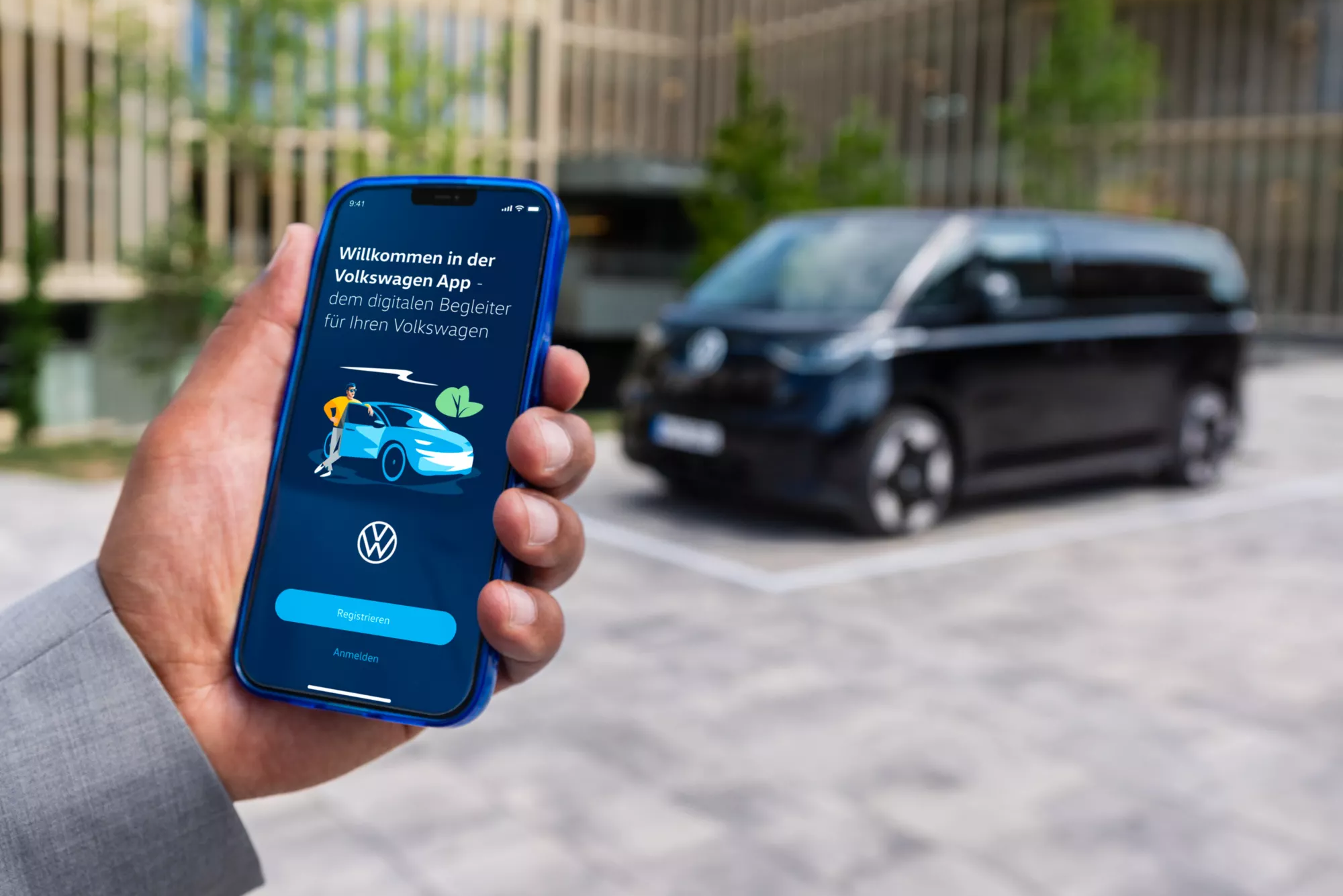 Mann meldet sich bei der Volkswagen App an, schwarzer ID. Buzz im Hintergrund