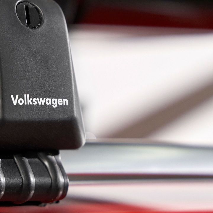 Nahaufnahme eines schwarzen Dachgepäckträgers mit Volkswagen-Logo auf einer silbernen Reling.