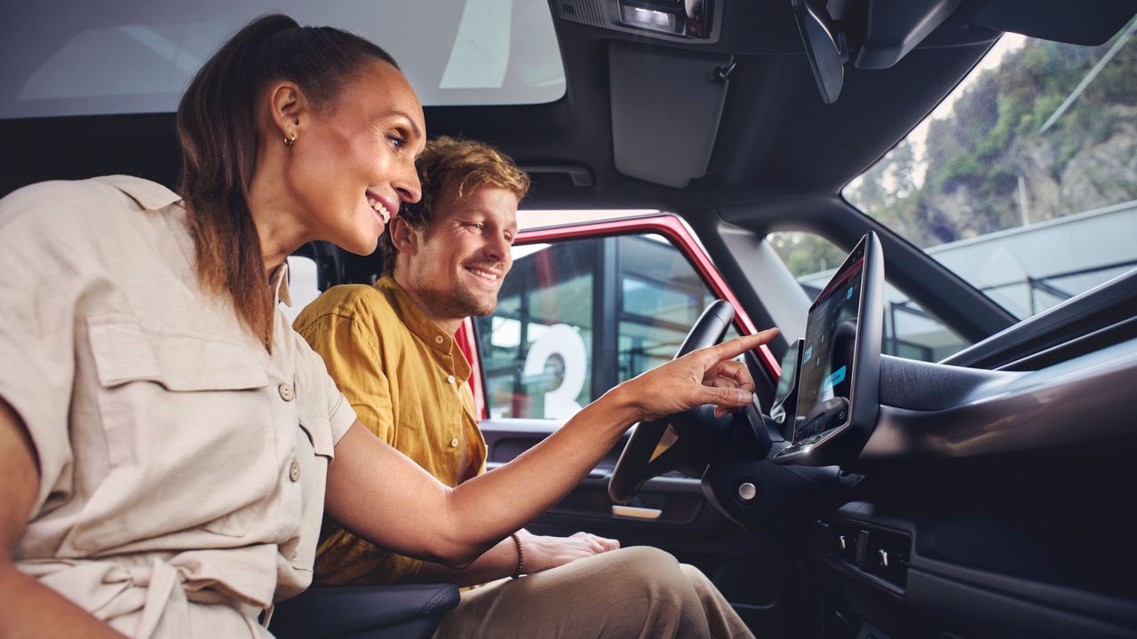 Ein Mann und eine Frau sitzen in einem Volkswagen Nutzfahrzeug und entdecken die Funktionen auf dem Touch Display.