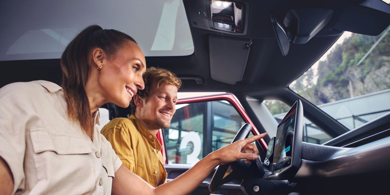 Ein Mann und eine Frau sitzen in einem Volkswagen Nutzfahrzeug und entdecken die Funktionen auf dem Touch Display.