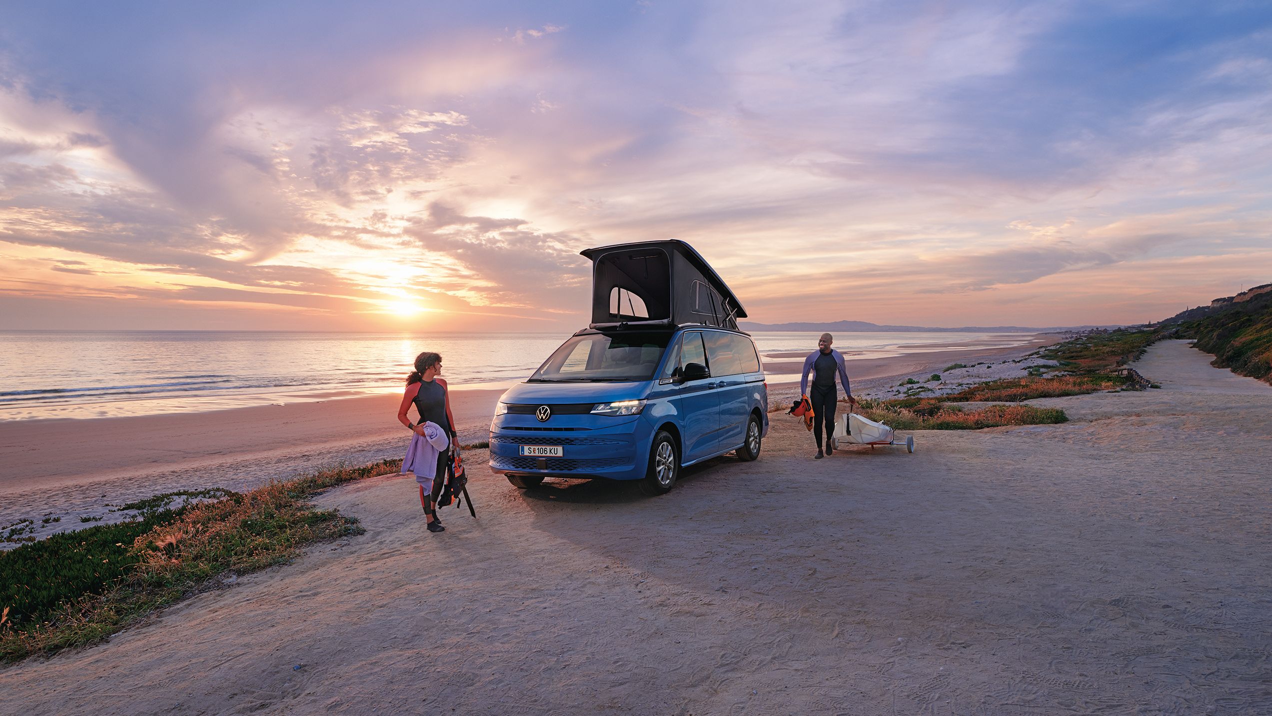 Neue California steht mit ausgeklapptem Dach an einem Strand bei Sonnenuntergang