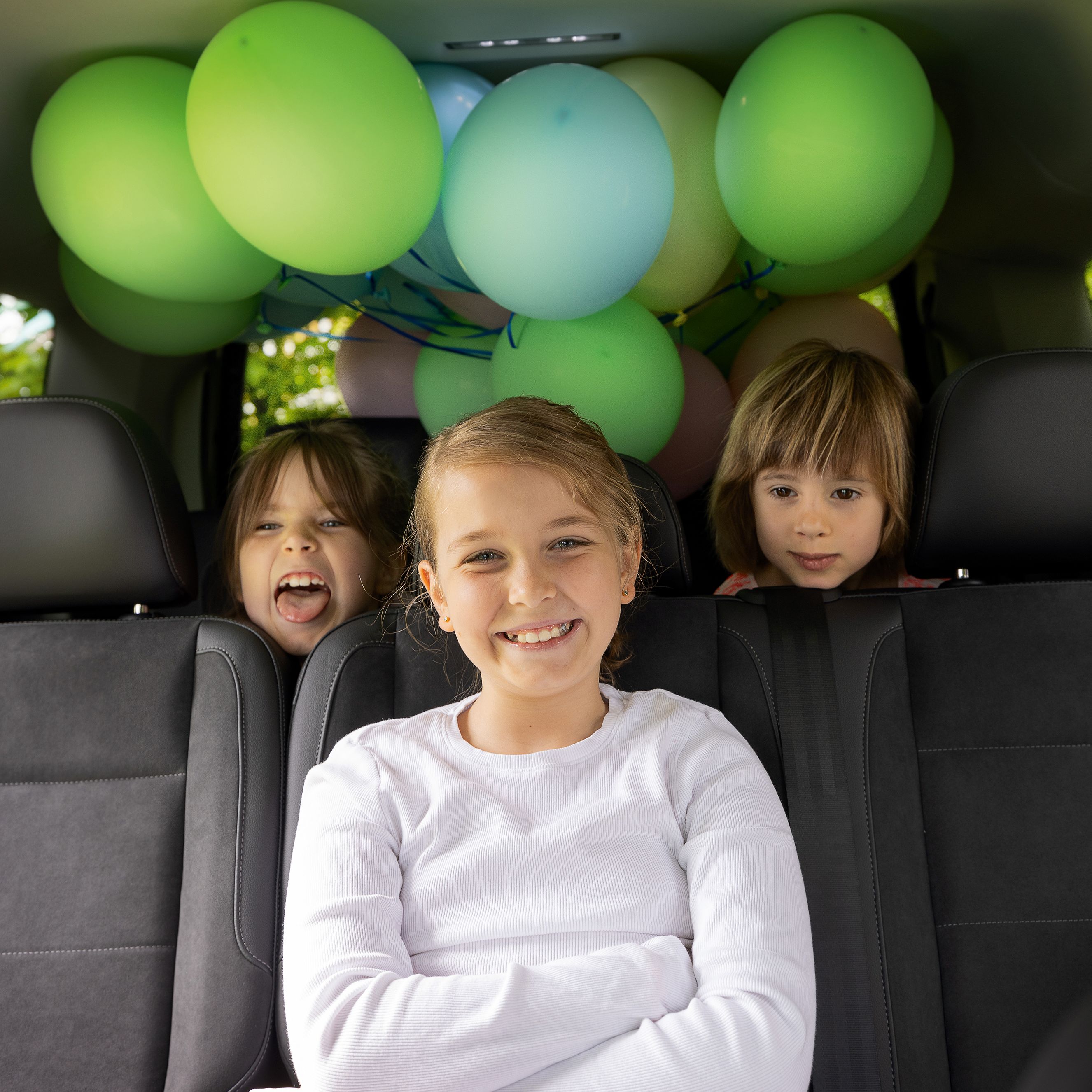 Kinder sitzen mit Luftballons im VW Caddy und haben Spaß