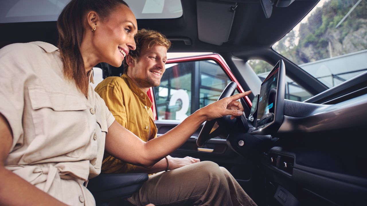 Ein Mann und eine Frau sitzen in einem Volkswagen Nutzfahrzeug und entdecken die Funktionen auf dem Touch Display.