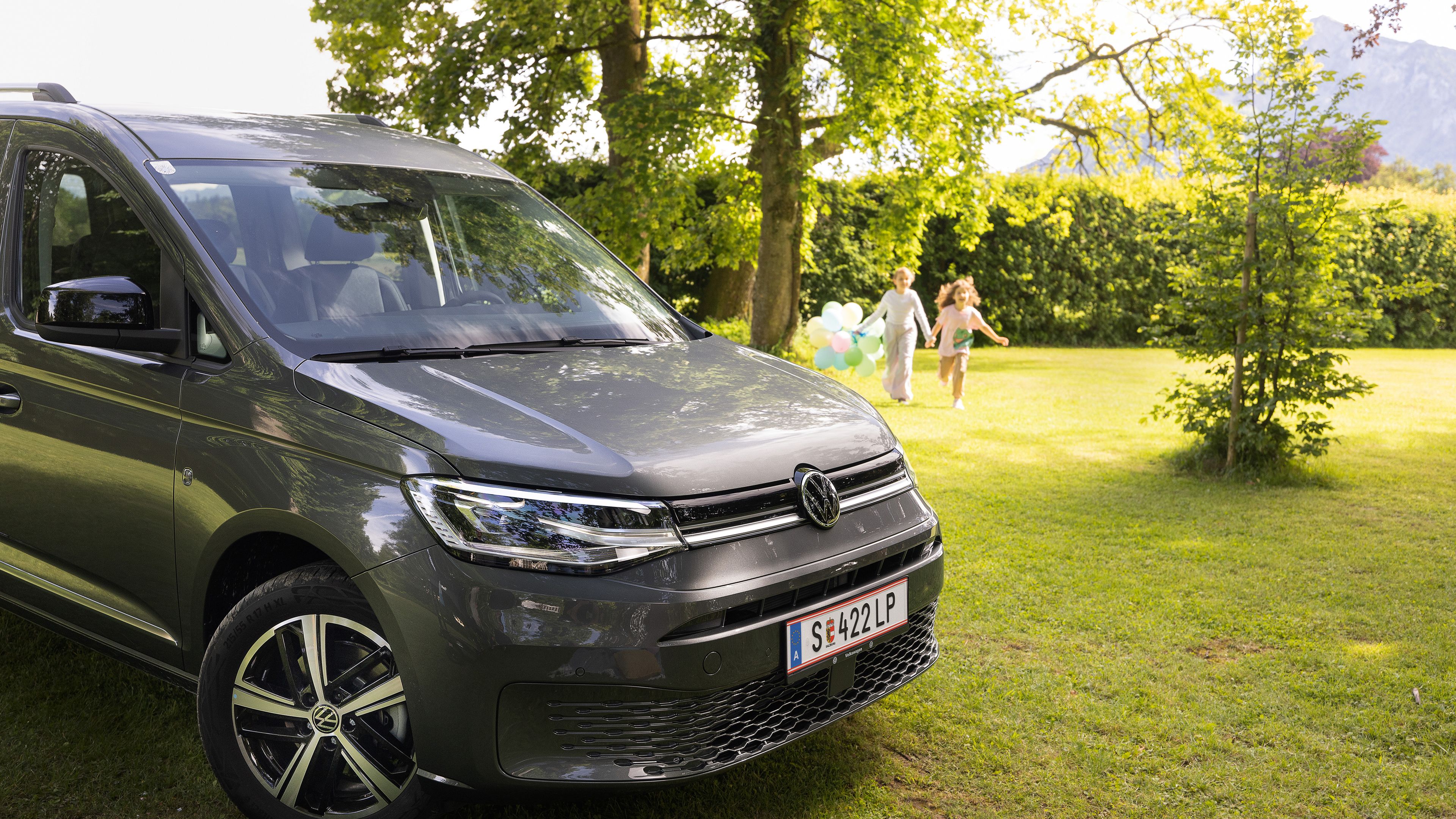 VW Caddy steht im Garten es wird ein Kindergeburtstag gefeiert und die Kinder spielen im Hintergrund
