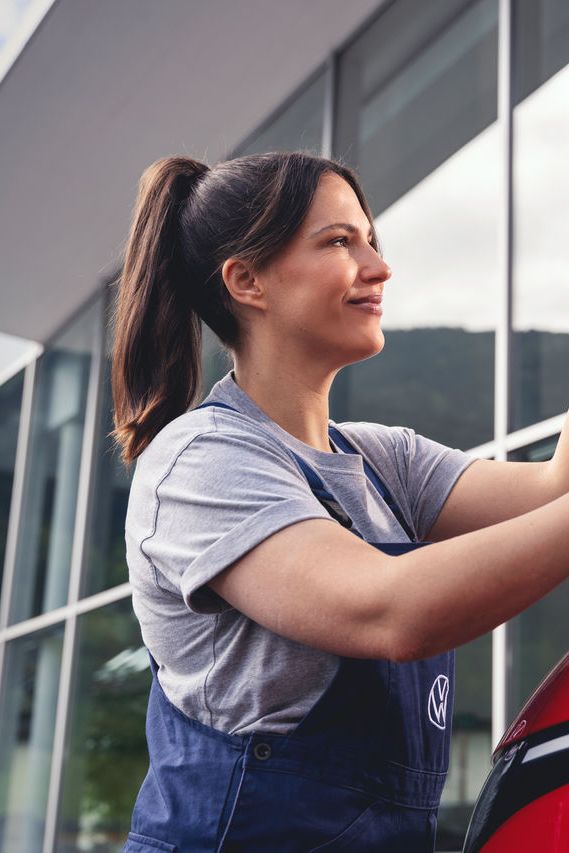 Eine Volkswagen Mechanikerin montiert Wischerblätter an einem Volkswagen.