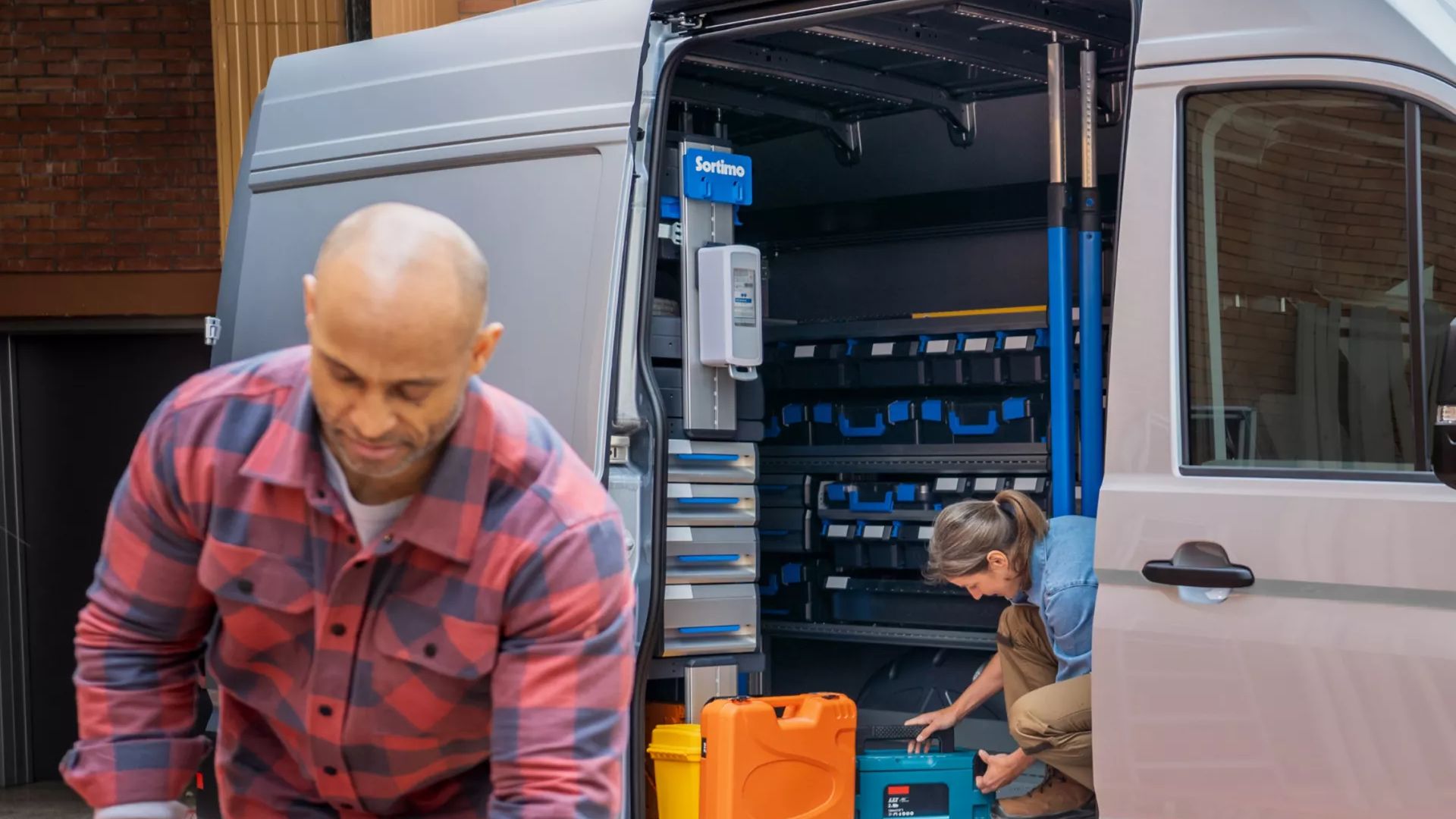 Zwei Handwerker nutzen einen VW Crafter als Arbeitsfahrzeug, geöffnete Schiebetür