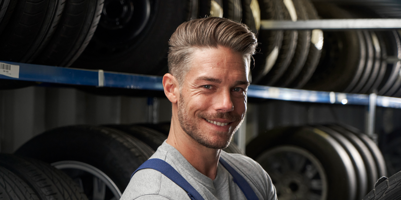 Ein VW Techniker vor Regalen mit Volkswagen Reifen und Rädern