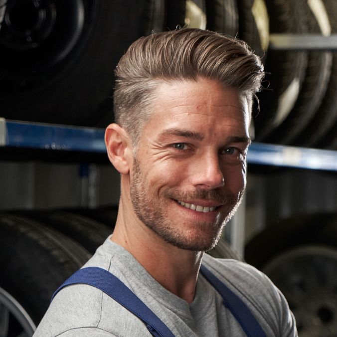 Ein VW Techniker vor Regalen mit Volkswagen Reifen und Rädern