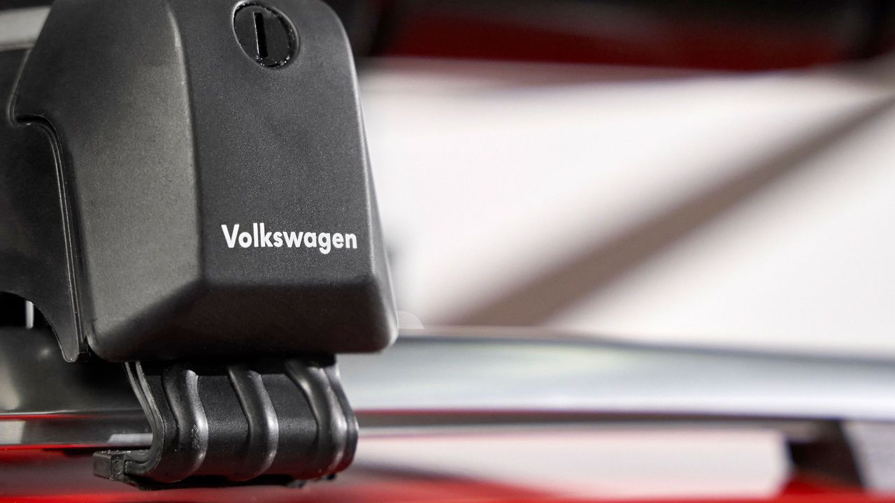 Nahaufnahme eines schwarzen Dachgepäckträgers mit Volkswagen-Logo auf einer silbernen Reling.