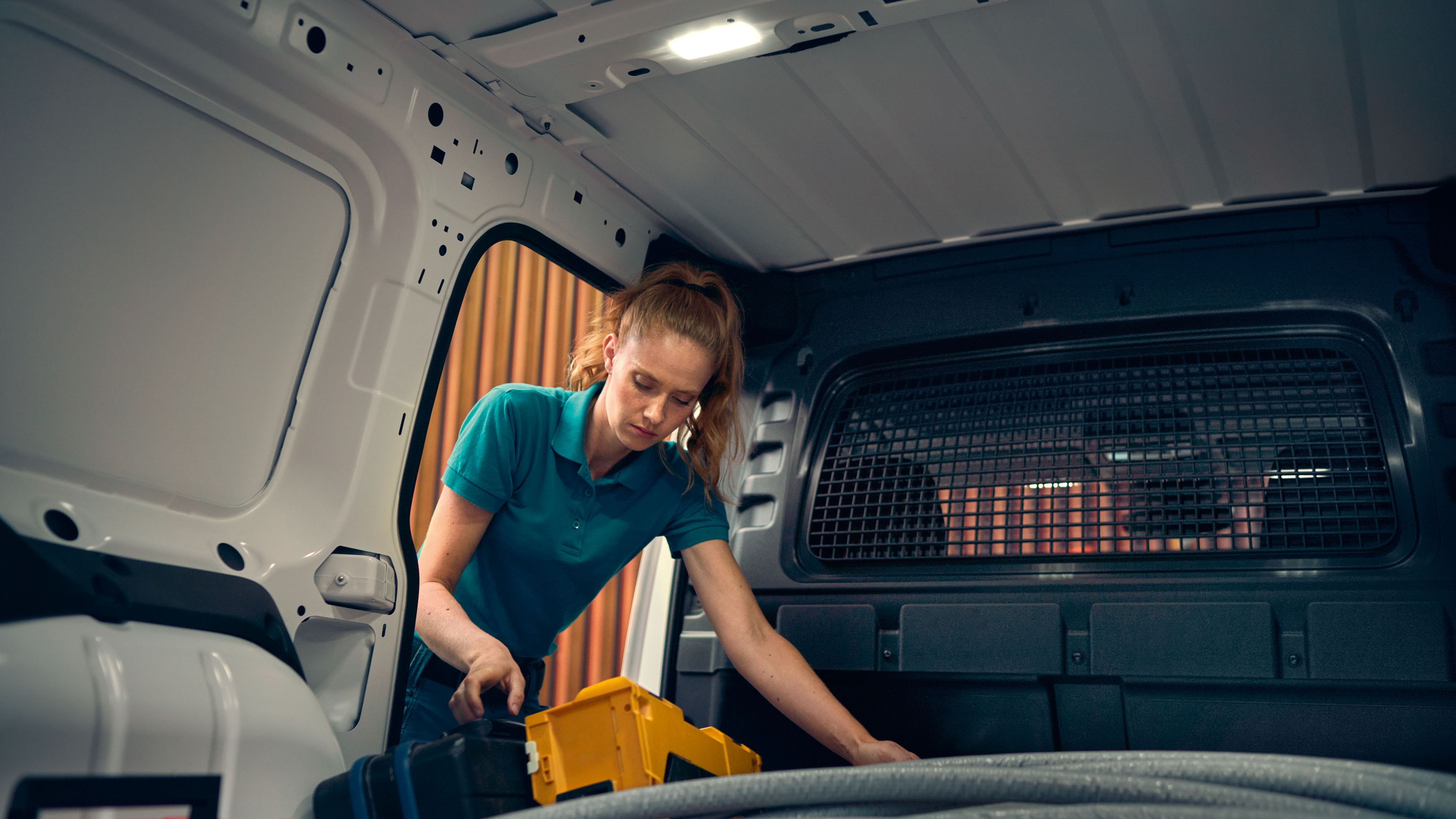 Eine Frau beim Beladen eines weißen VW Caddy Cargo.