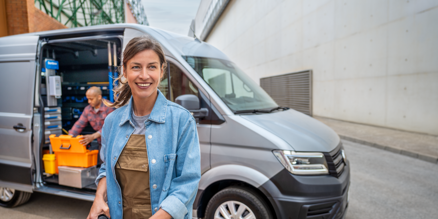 Eine Frau vor einem silbernen Crafter Kastenwagen, ein Mann kniet auf der Ladefläche.