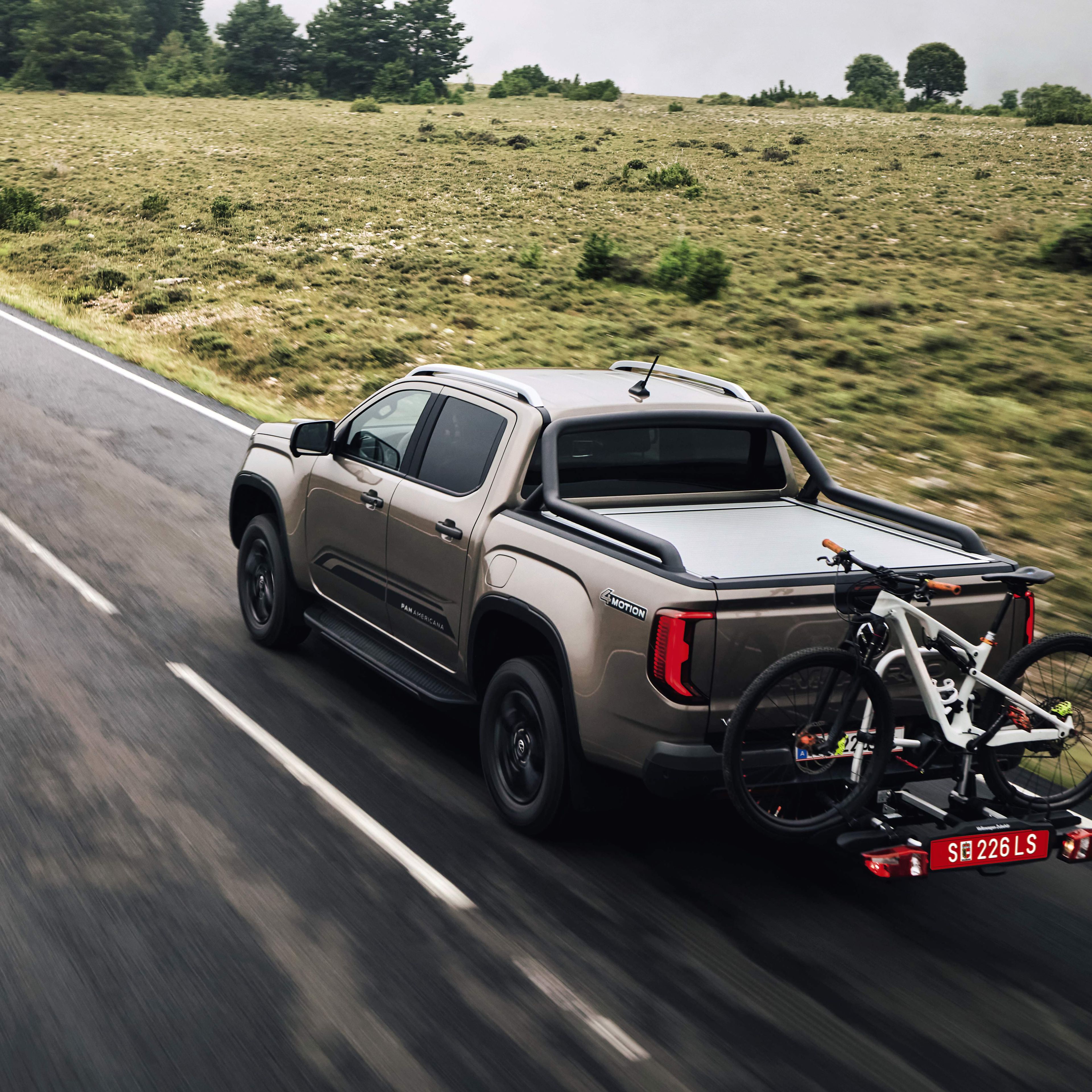 Amarok mit Fahrradträger fährt bei Nässe über eine Landstraße