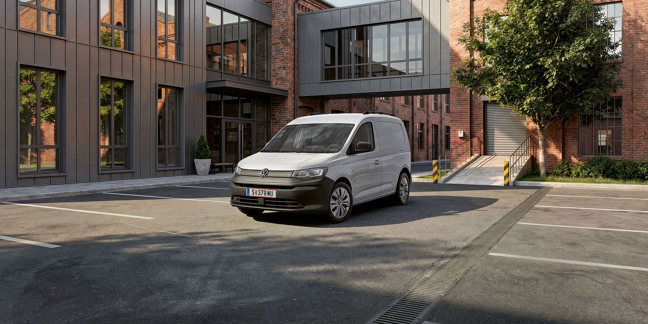 Der neue Caddy Cargo in Weiß steht vor Gebäude.