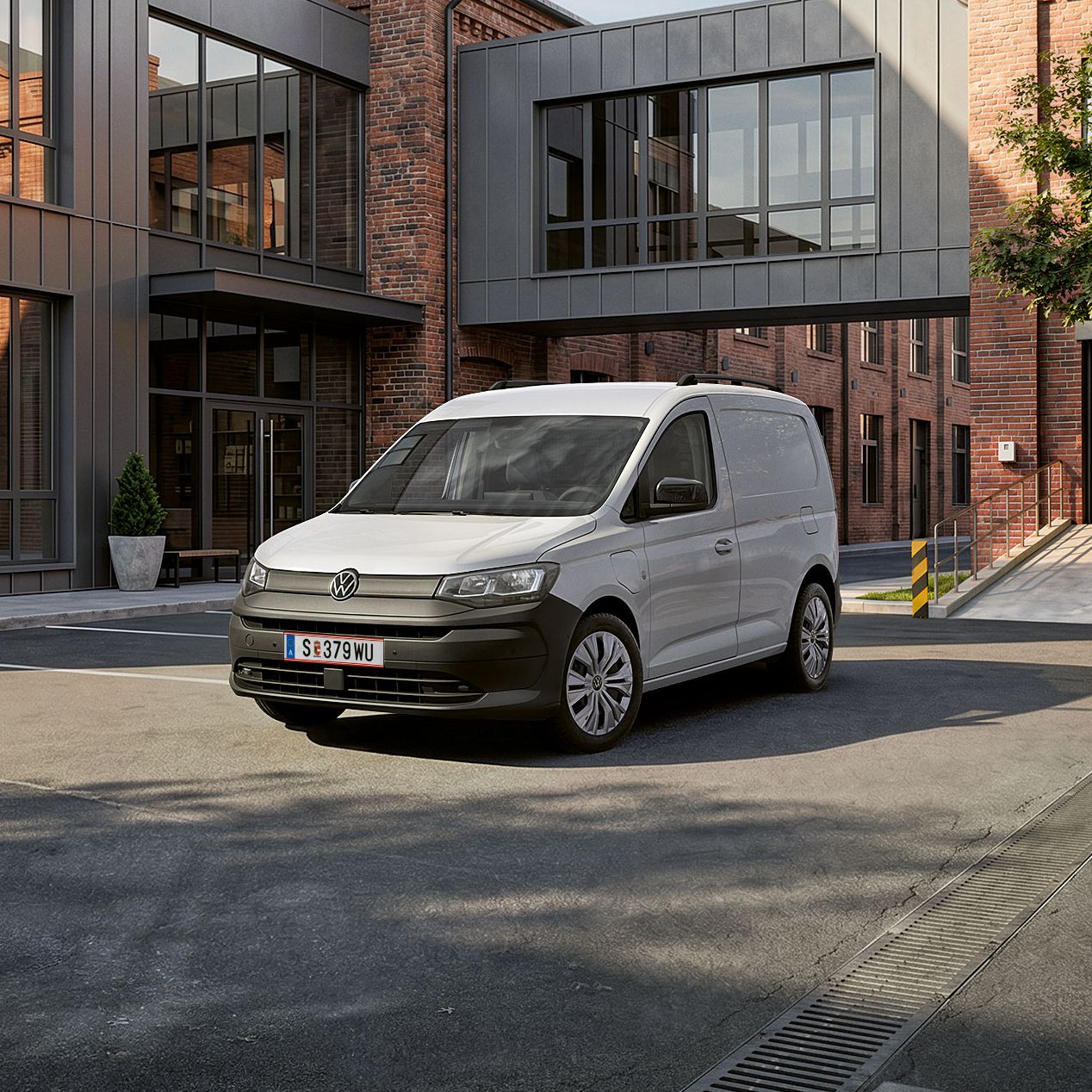 Der neue Caddy Cargo in Weiß steht vor Gebäude.