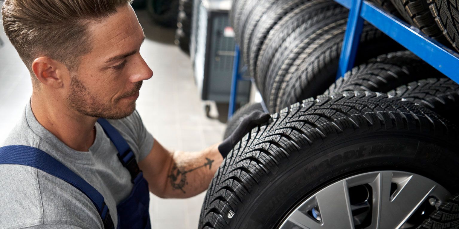 Ein Volkswagen Service Techniker nimmt einen Reifen aus einem Lagerregal