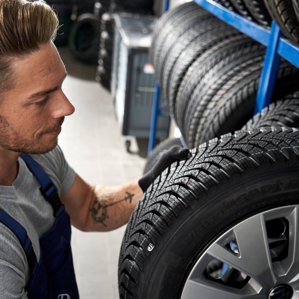 Ein Volkswagen Service Techniker nimmt einen Reifen aus einem Lagerregal