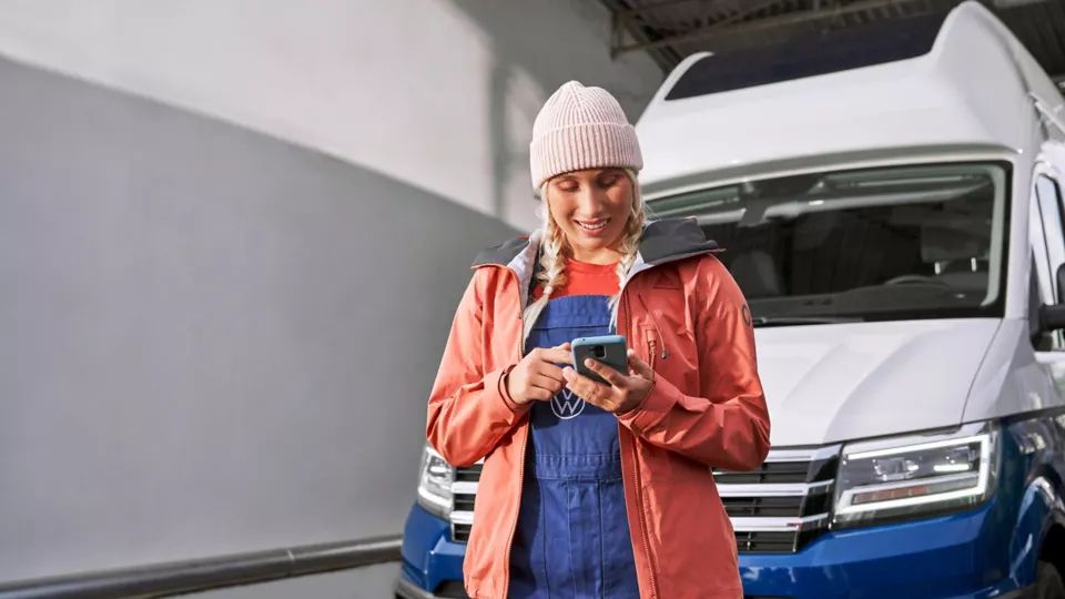 Frau steht mit Smartphone vor Grand California.