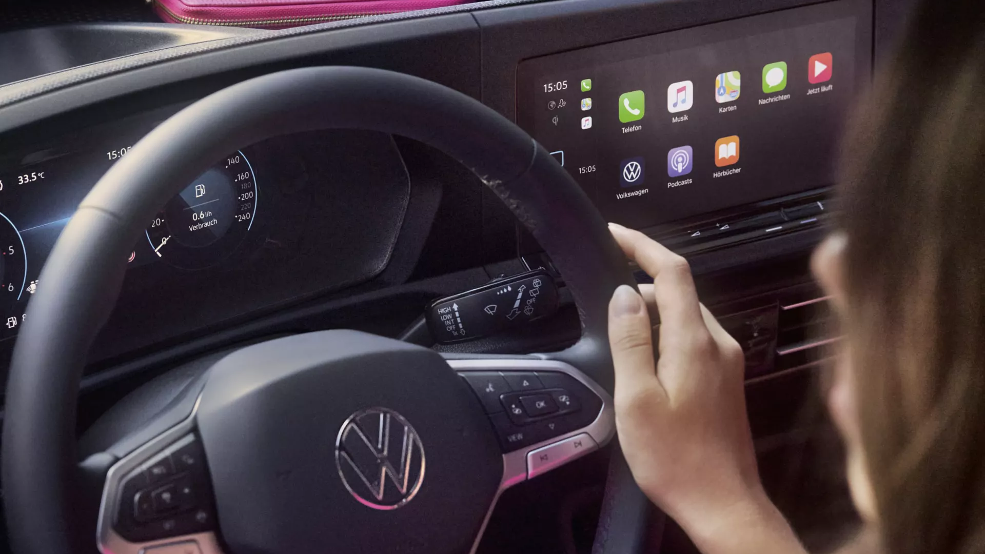 Fahrerin berührt Mulitfunktionslenkrad eine Caddys, Infotainment - Bildschirm im Hintergrund