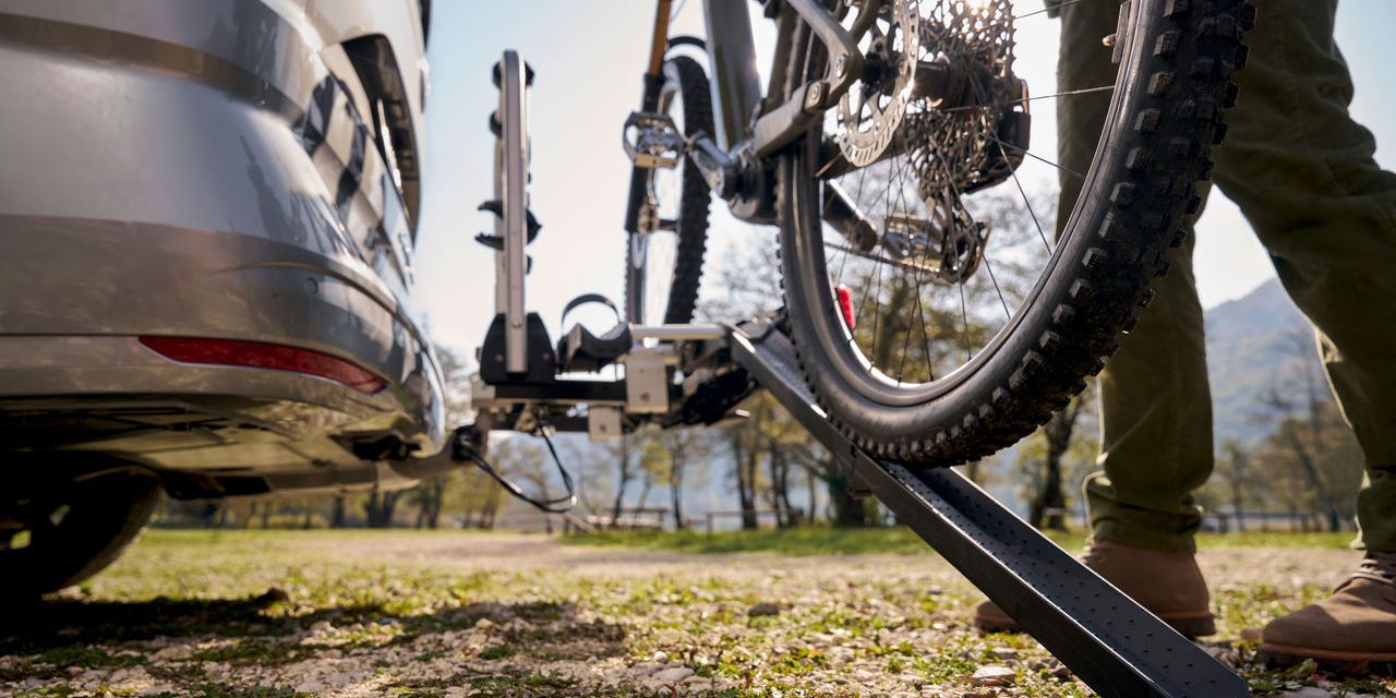 Ein Mann befestigt ein Fahrrad an einem Volkswagen Fahrrad Heckträger.