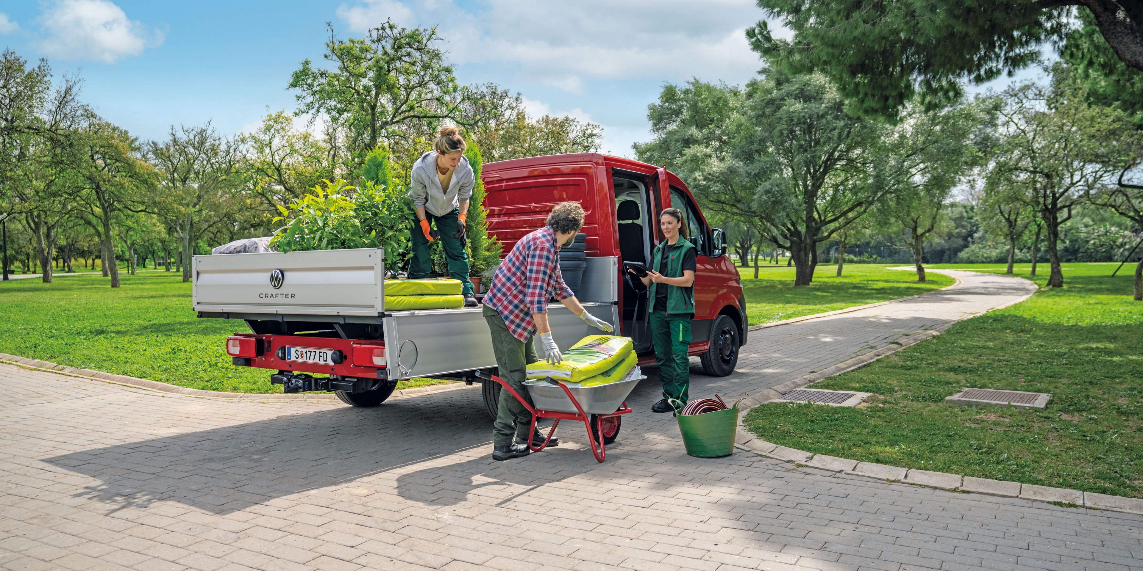 Drei Personen entladen einen Volkswagen Crafter Pritschenwagen