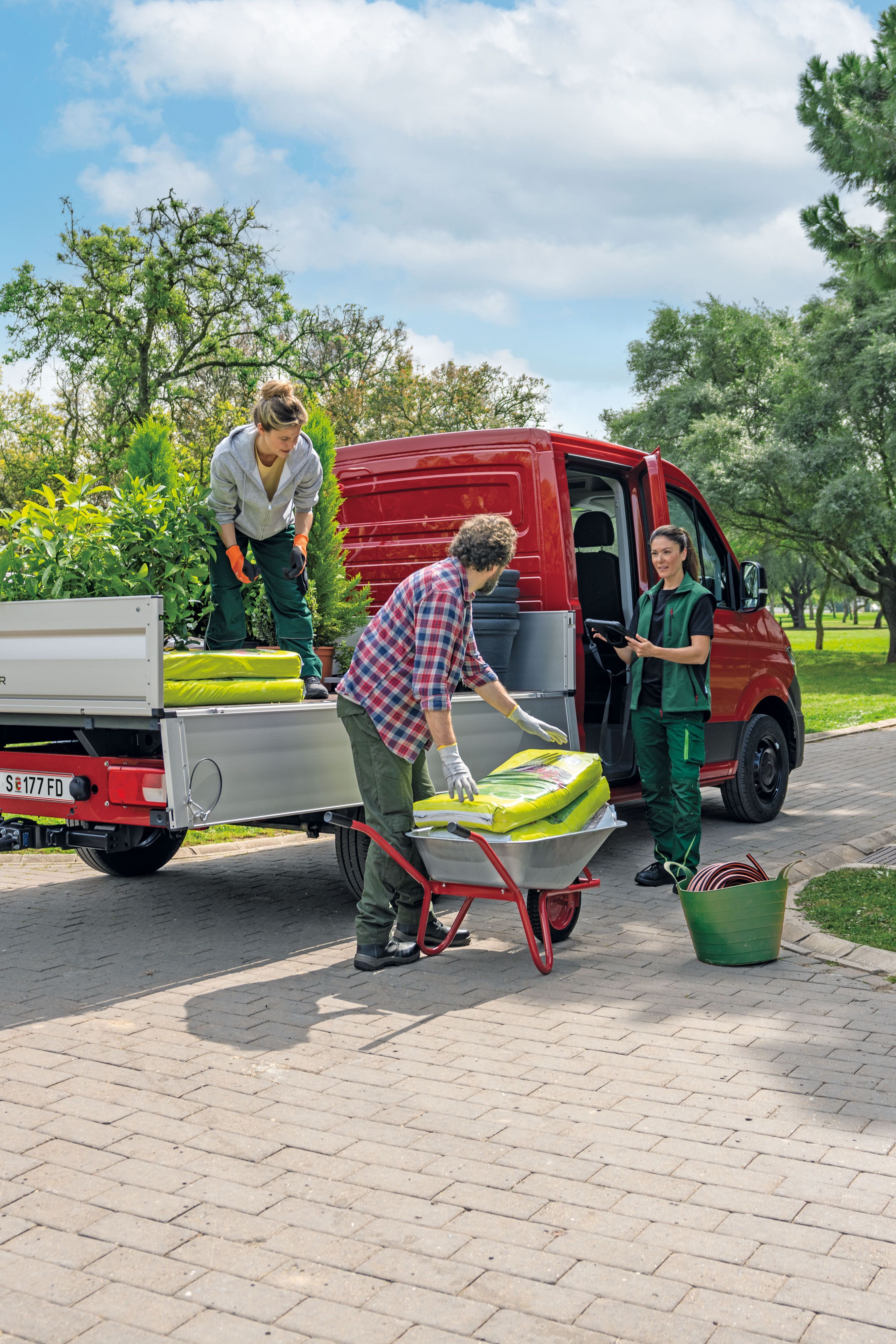 Drei Personen entladen einen Volkswagen Crafter Pritschenwagen