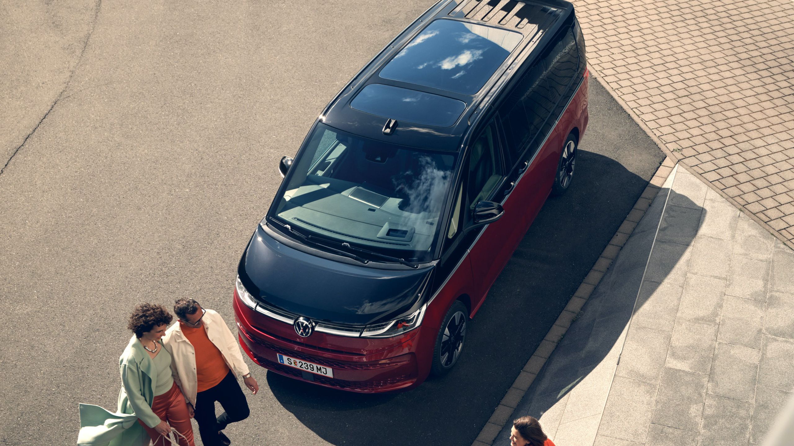 Parkender VW Multivan von oben. Familie steht vor dem Fahrzeug.
