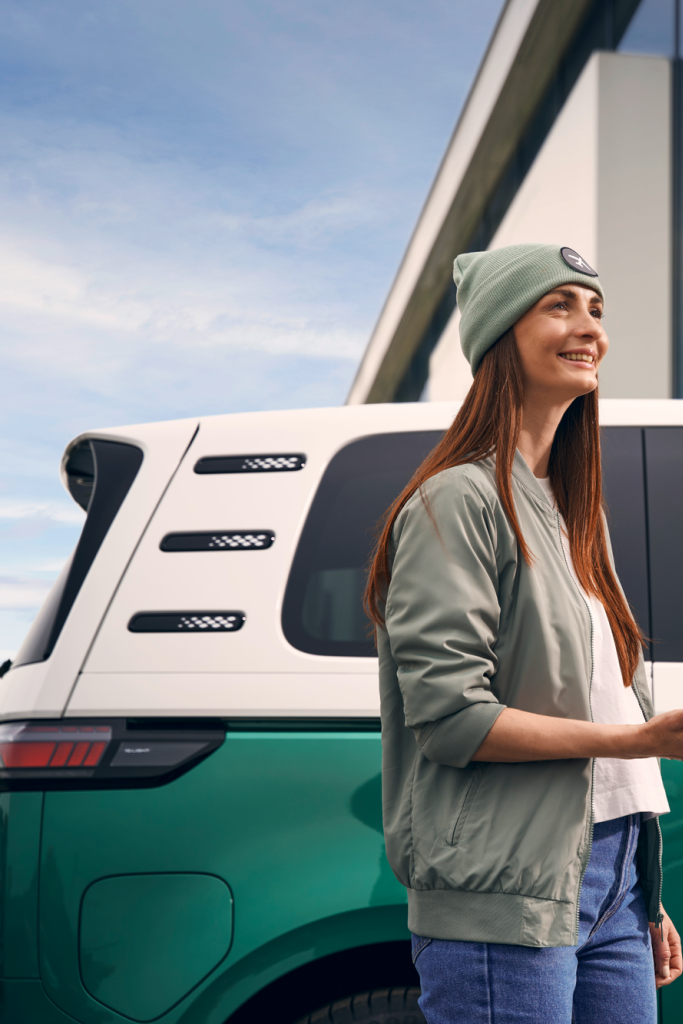 Ein Volkswagen Mitarbeiter bei der Schlüsselübergabe an eine Kundin. Im Hintergrund ist ein ID. Buzz zu sehen.