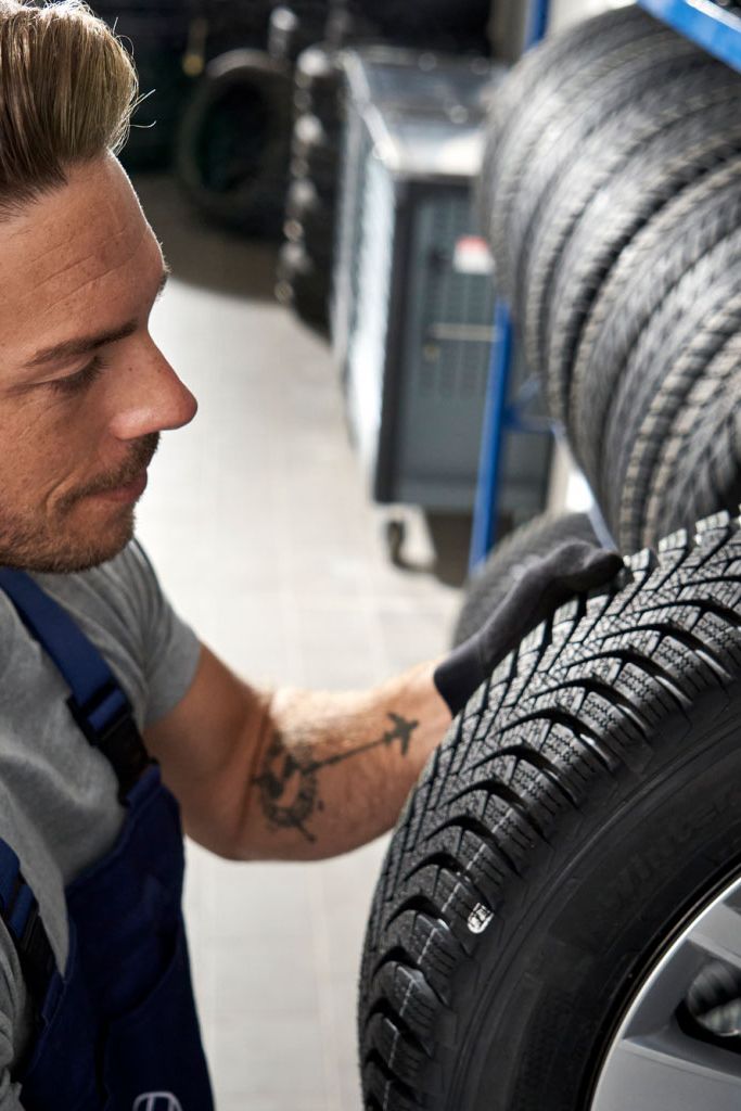 Ein Volkswagen Service Techniker nimmt einen Reifen aus einem Lagerregal