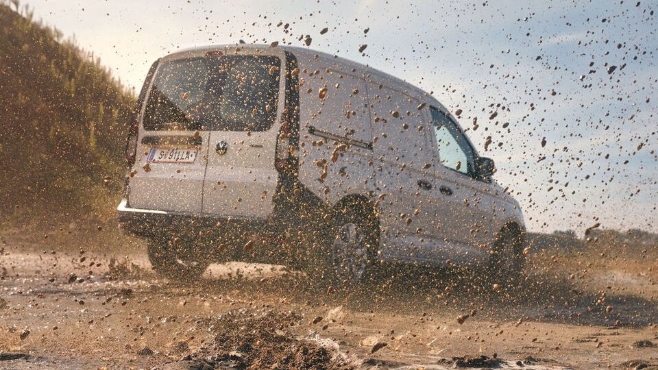 VW Caddy in weiß, fährt durch matschige Landschaft
