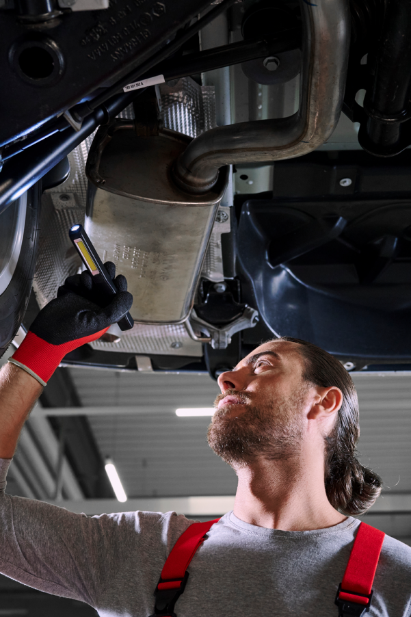 Ein VW Mechaniker bei der Kontrolle der Stoßdämpfer von einem VW Nutzfahrzeug