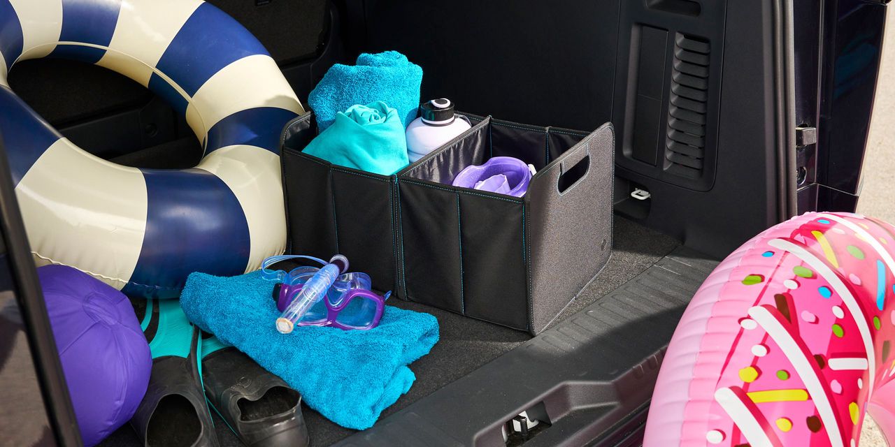 Ein offener Kofferraum eines Volkswagen Nutzfahrzeugs mit Blick auf Strand- und Badeutensilien, darunter bunte Schwimmringe, Handtücher und Taucherbrille. 