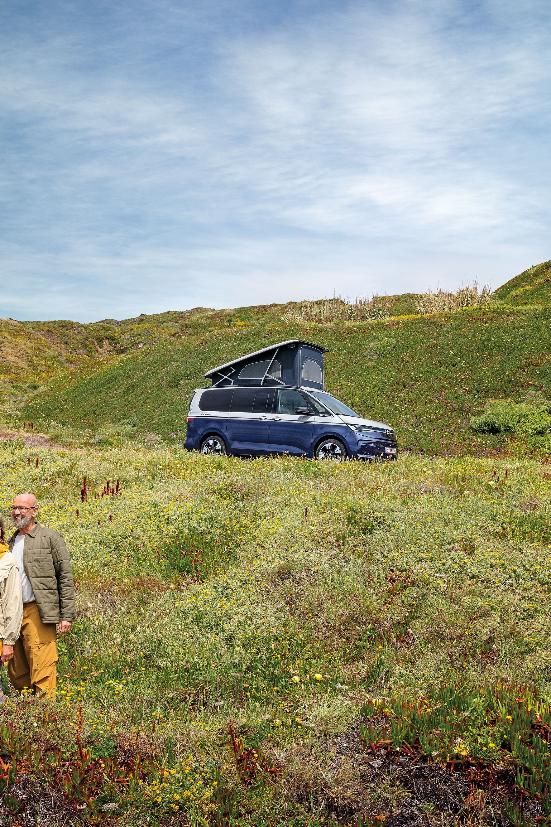 Ein VW California steht auf einer Schotterstraße am Meer
