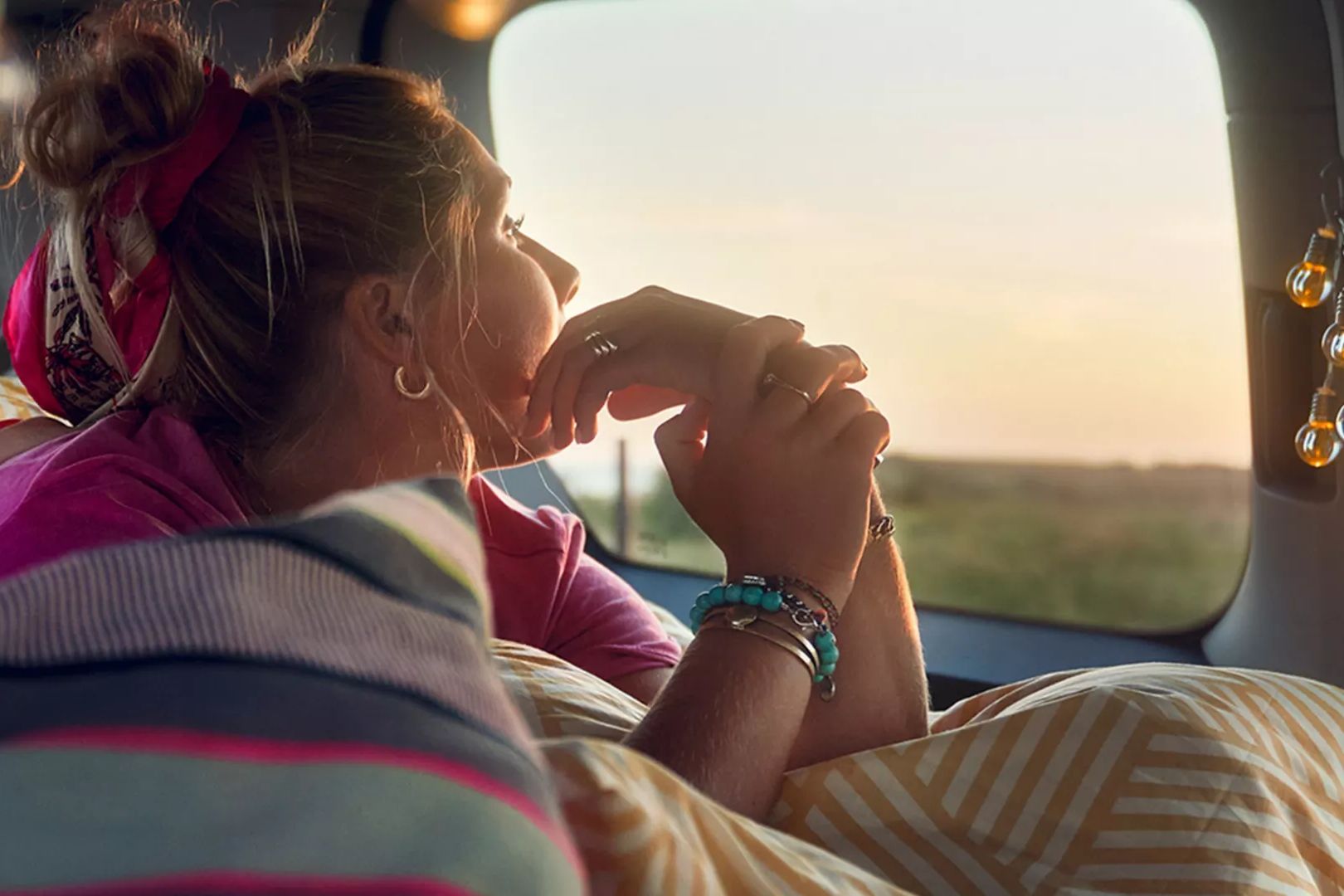 Ein Mädchen liegt auf der Liegefläche eines VW Caddys und schaut aus dem Fenster