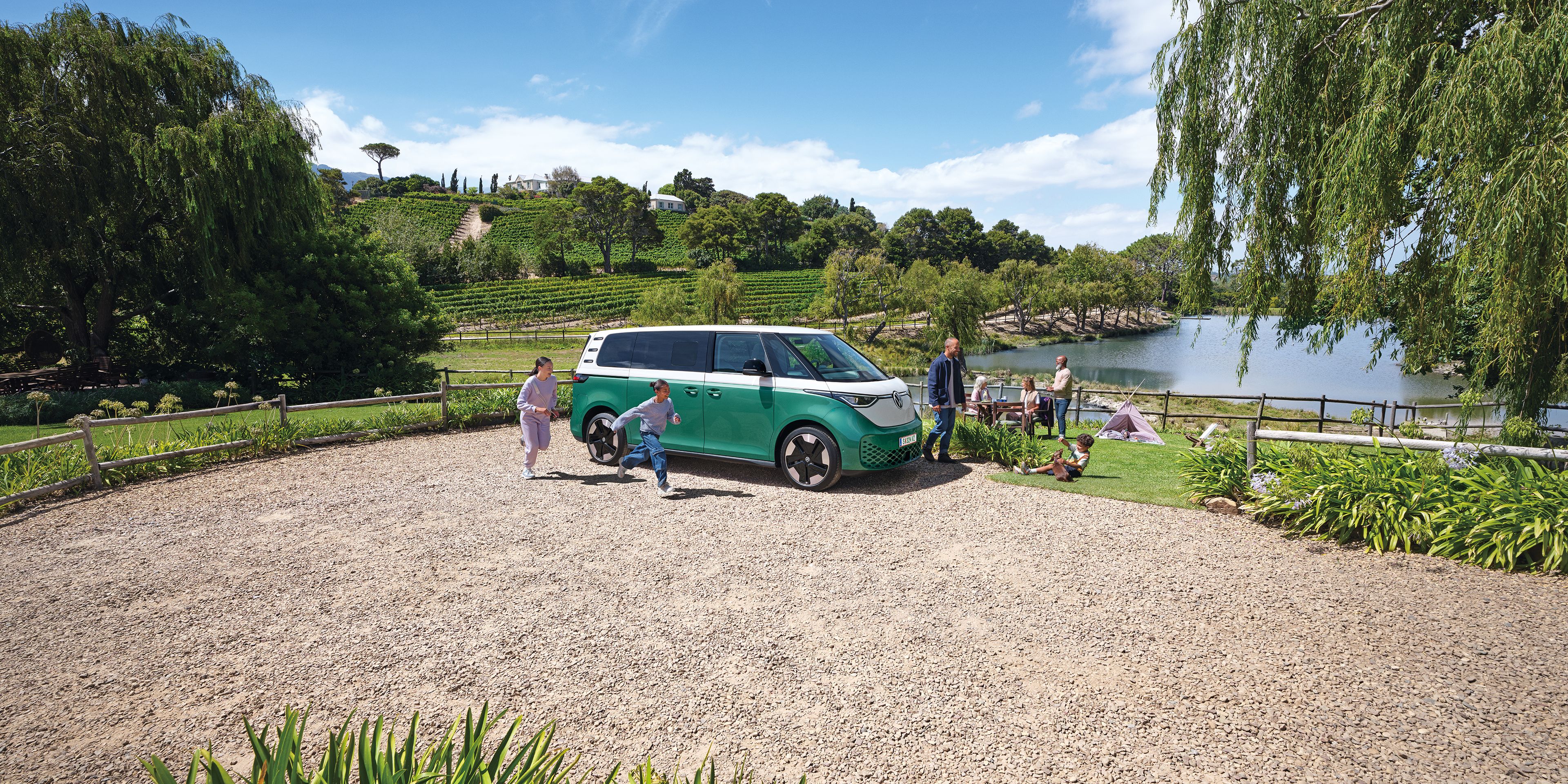 Ein ID. Buzz parkt an einem See, eine Familie bewegt sich um das Auto herum