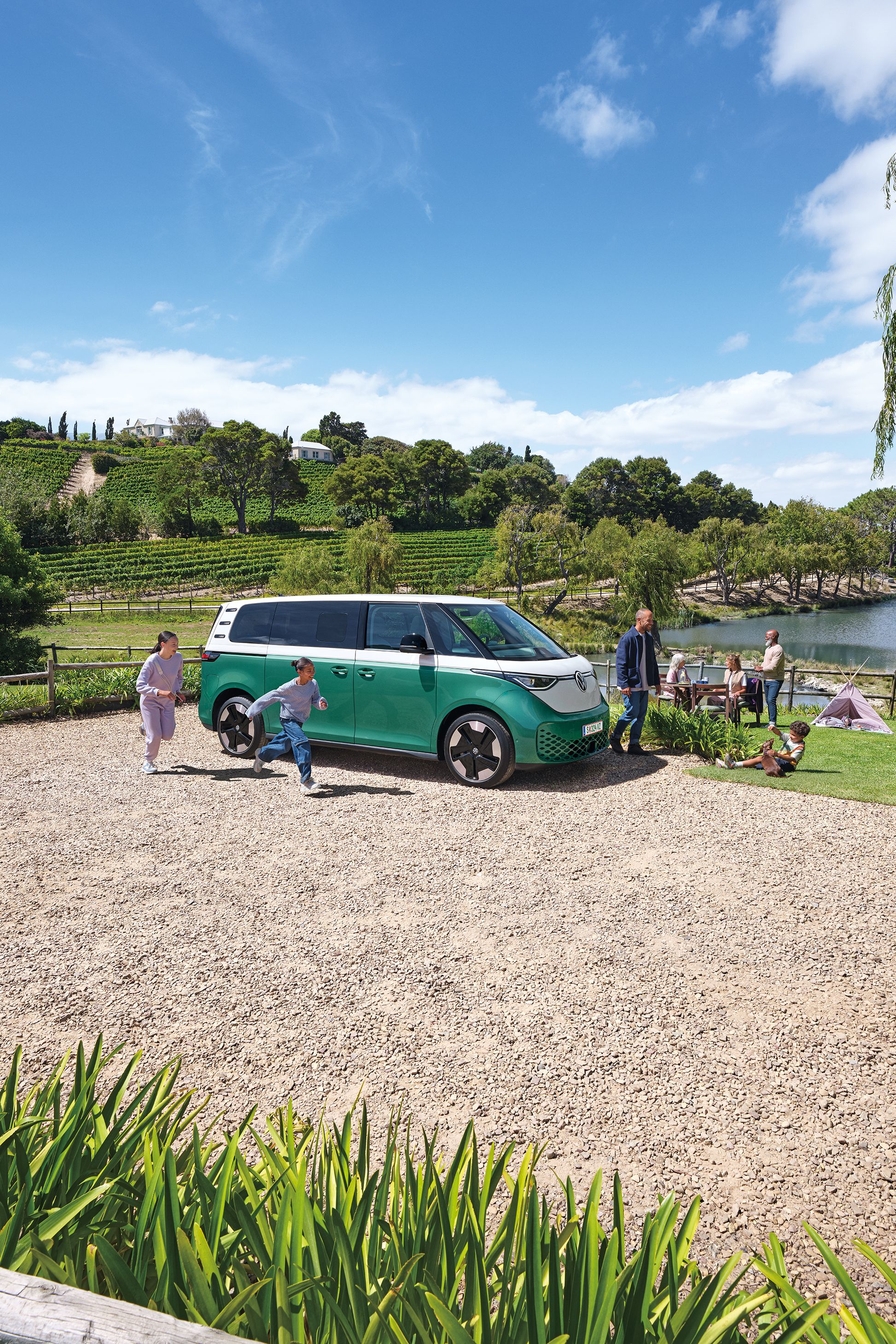 Ein ID. Buzz parkt an einem See, eine Familie bewegt sich um das Auto herum