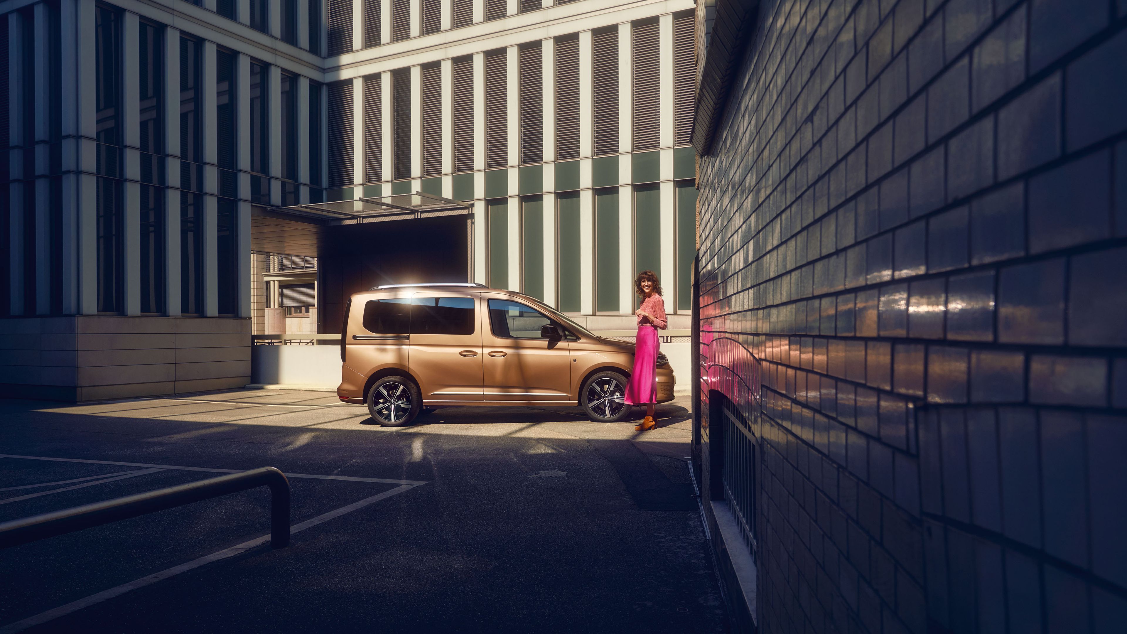 Eine Frau steht neben einem VW Caddy der von der Seite zu sehen ist.