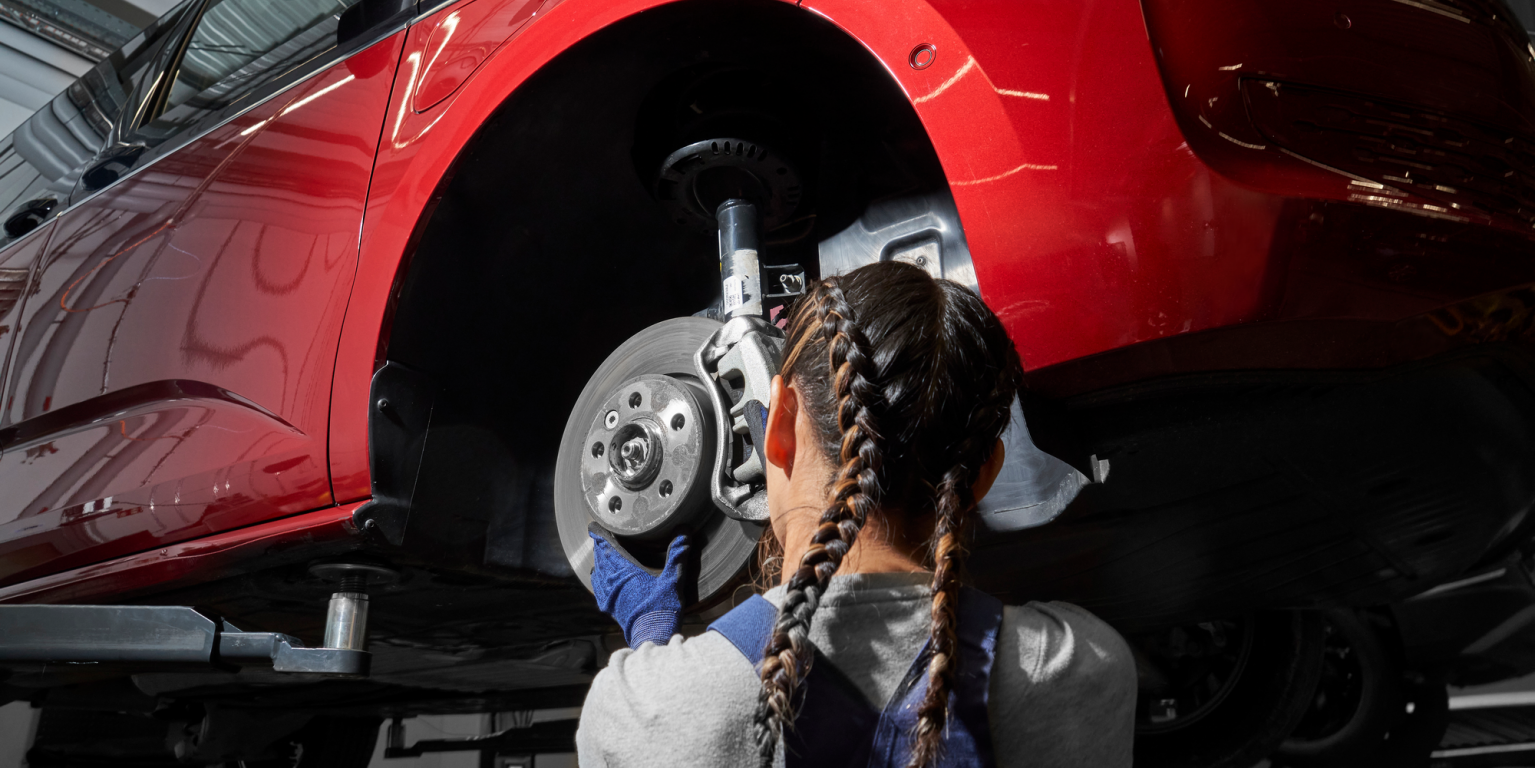 Eine VW Mechanikerin wechselt die Bremsscheiben bei einem VW Nutzfahrzeug