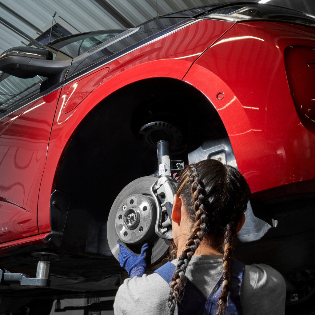 Eine VW Mechanikerin wechselt die Bremsscheiben bei einem VW Nutzfahrzeug