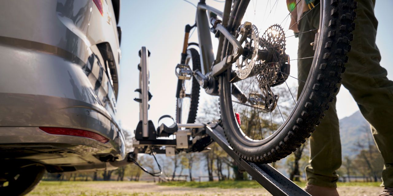 Ein Mann befestigt ein Fahrrad an einem Volkswagen Fahrrad Heckträger.