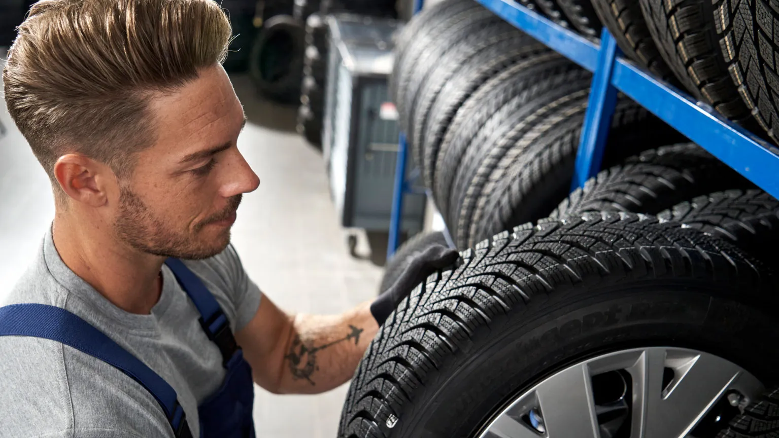 Ein Volkswagen Service Techniker nimmt einen Reifen aus einem Lagerregal