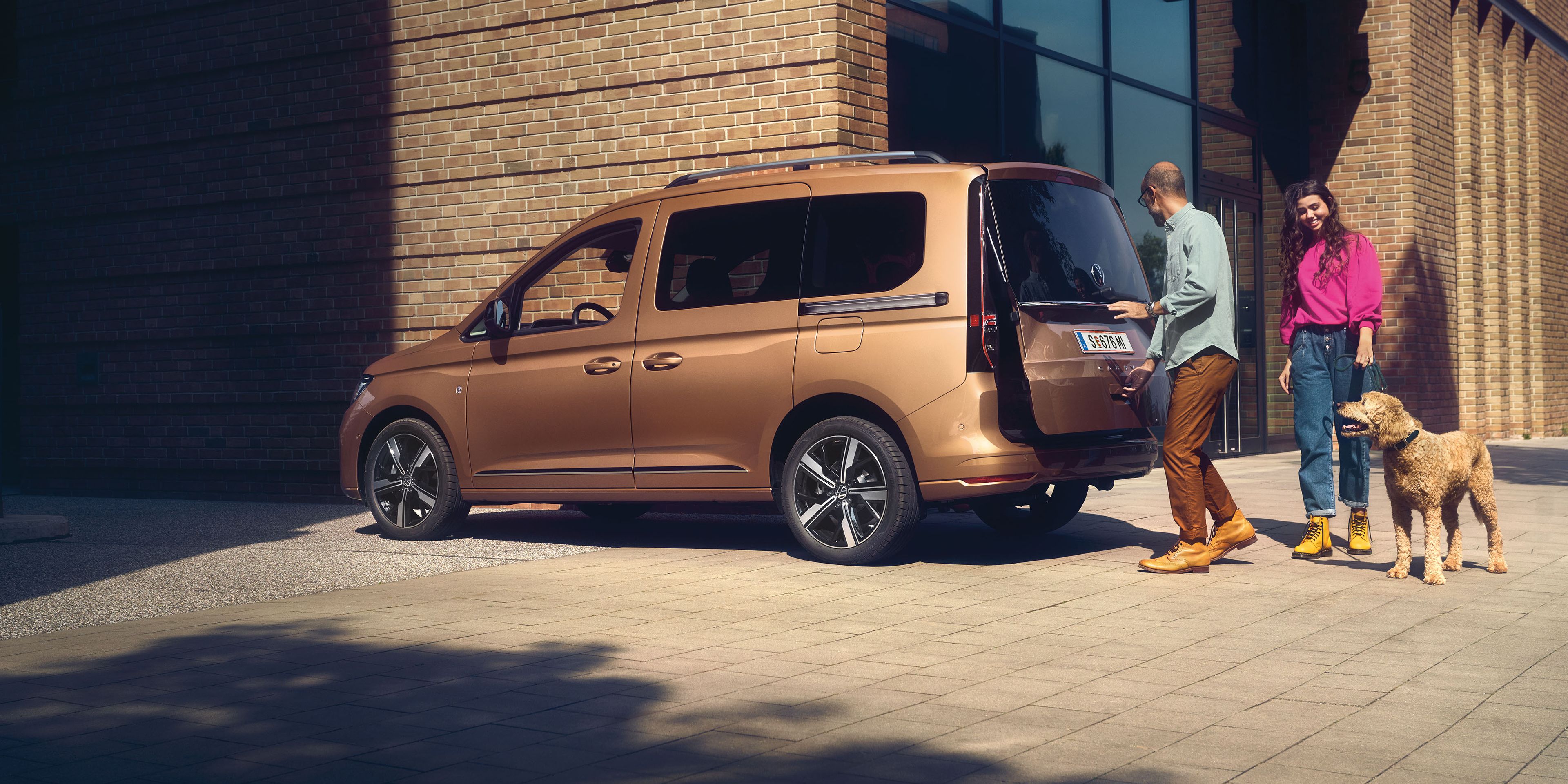 Ein Mann öffnet die Heckklappe mit Fenster eines VW Caddy.