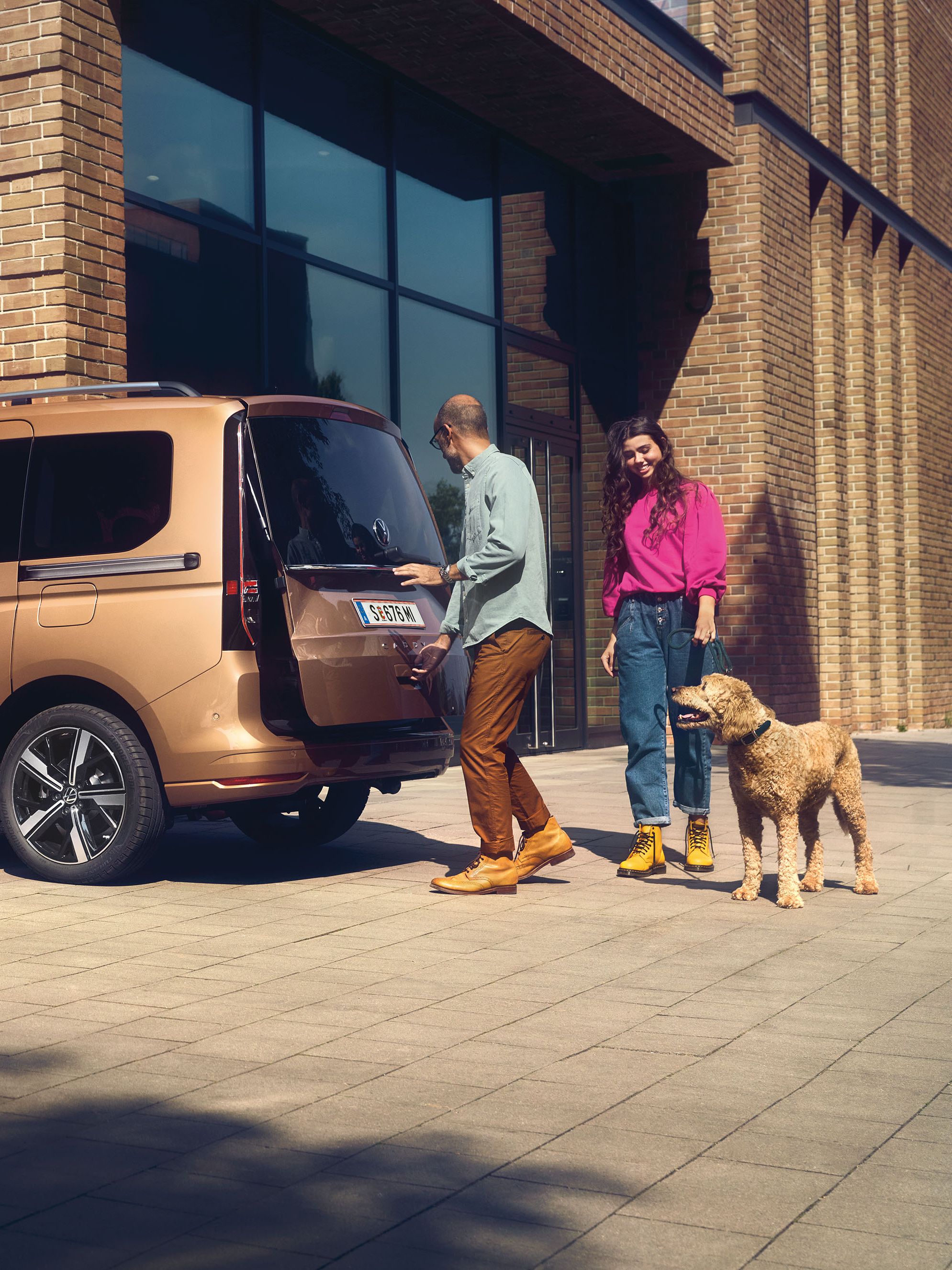 Ein Mann öffnet die Heckklappe mit Fenster eines VW Caddy.