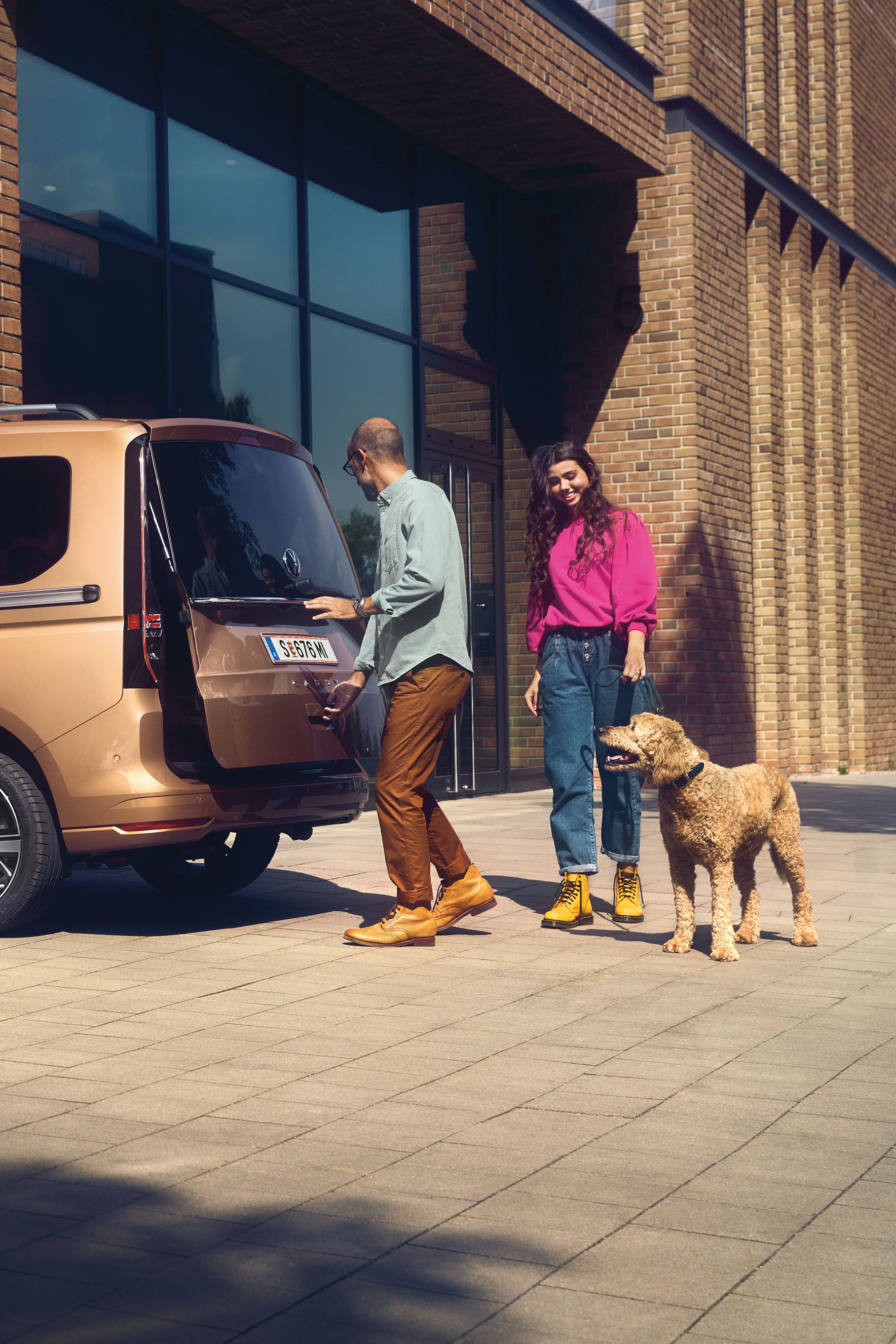 Ein Mann öffnet die Heckklappe mit Fenster eines VW Caddy.