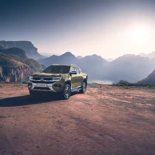 Ein Volkswagen Amarok steht auf einer felsigen Fläche mit Bergen im Hintergrund.