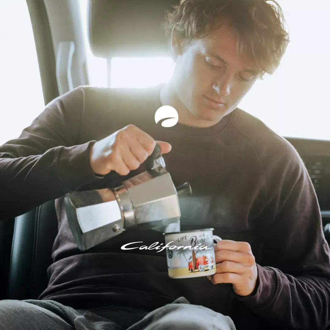 Eine Person gießt in eine California einen Kaffee in eine California Becher. 