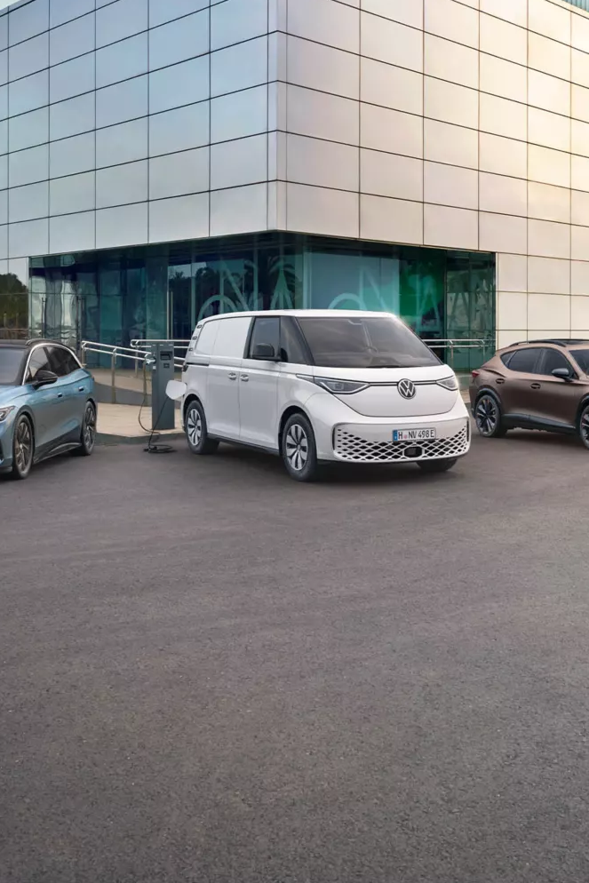Eine Reihe von Fahrzeugen steht vor einem modernen Gebäude. Es sind verschiedene Autotypen, darunter Limousinen, ein Van und ein Sportwagen. Die Autos sind in unterschiedlichen Farben lackiert.