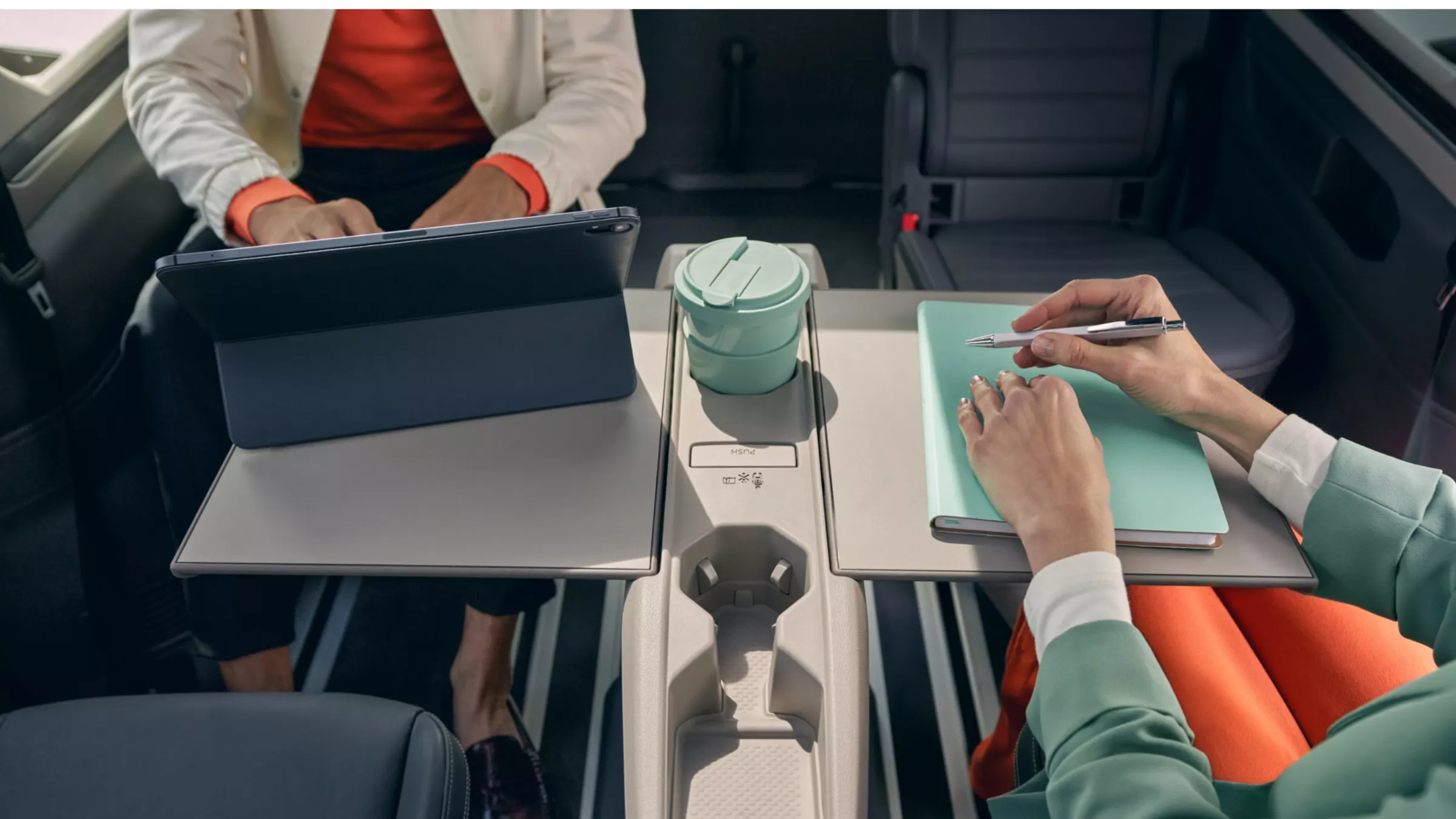 Zwei Personen sitzen im Fond des neuen VW Multivans und arbeiten
