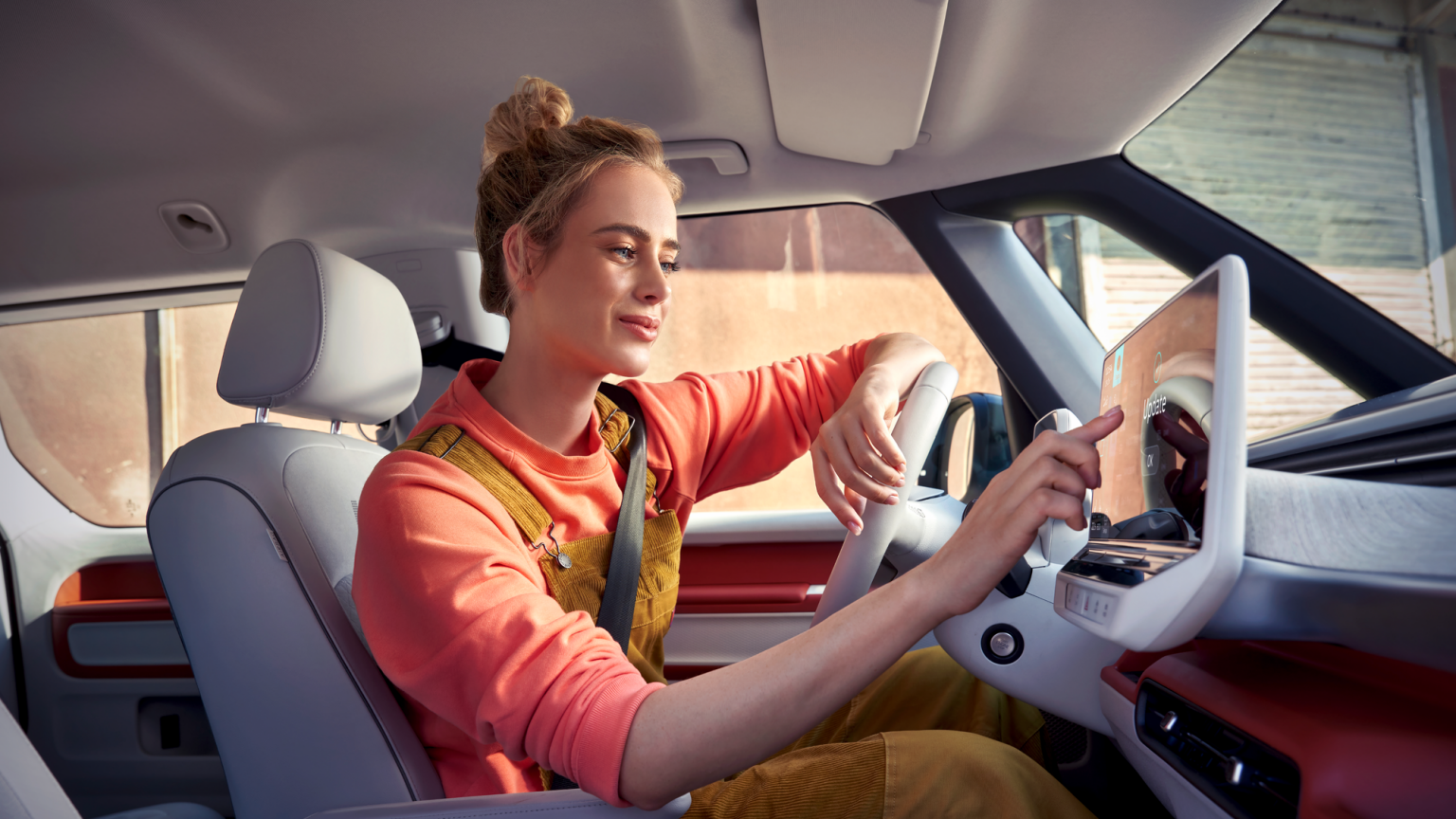 Eine Frau sitzt in einem VW und zeigt auf das moderne Display