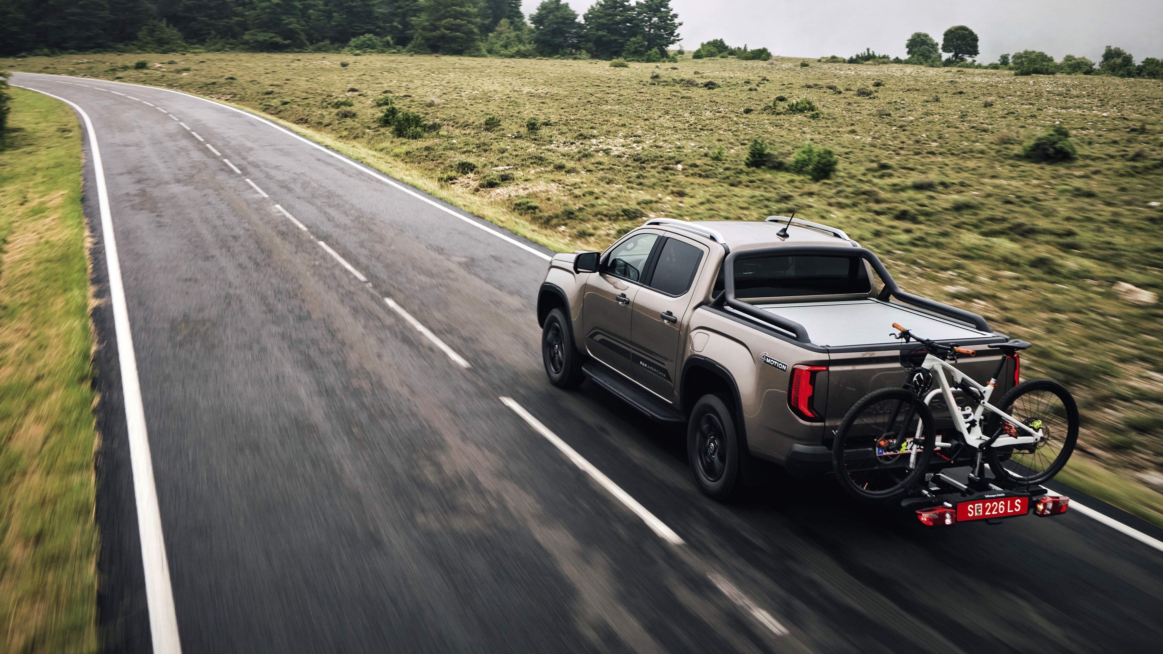 Amarok mit Fahrradträger fährt bei Nässe über eine Landstraße