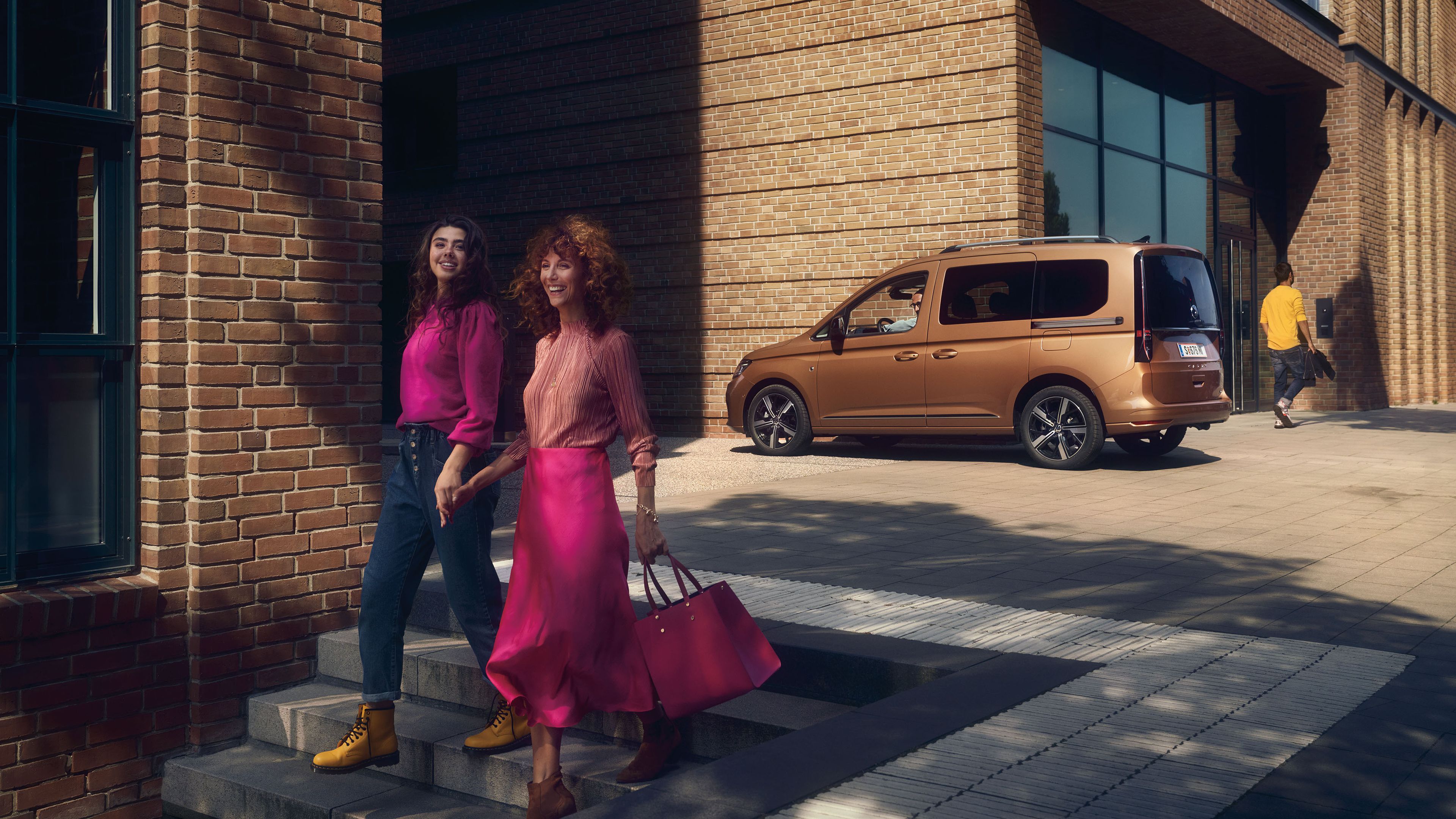 Die Mutter geht mit ihrer Tochter die Stiege hinunter, dahinter ist ein VW Caddy zu sehen.